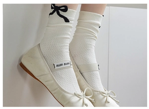 Close-up of cream knit socks featuring black bow detail with chic ballet flats