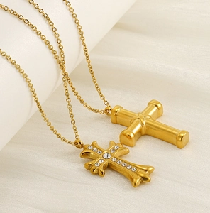 Detail view of gold-plated cross pendants with white rhinestones on ivory silk fabric