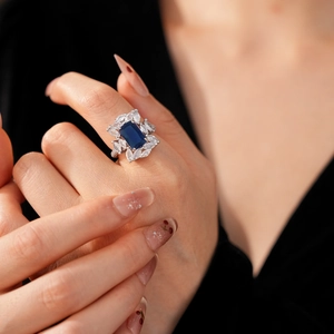 Gros plan d'une bague de luxe avec zircon bleu marine et dentelle ajourée sur la main