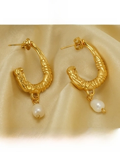 Macro detail of gold U-shaped titanium earrings with twisted texture and pearl drop
