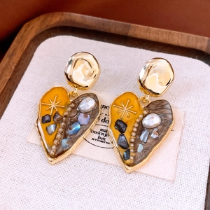 Detailed close-up of vintage heart earrings with gold metal, pearls and enamel inlay