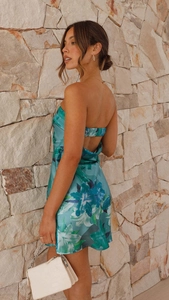 Détail d'une robe courte satinée à fleurs bleu aqua avec dos nu et texture lisse