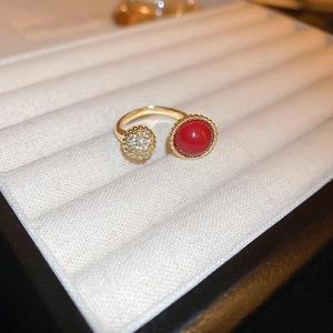 Detailed close-up of golden dragon ring with red bead and pavé zircon on velvet tray