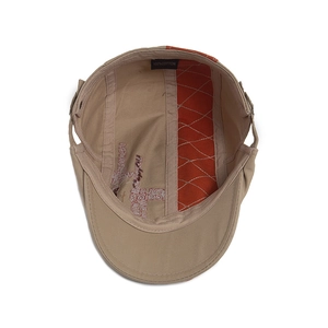 Interior view of beige cotton flat cap showing 100% cotton label and orange stitching detail