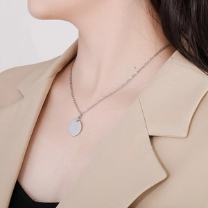 Gros plan d'un collier pendentif rond minimaliste en acier inoxydable sur un mannequin