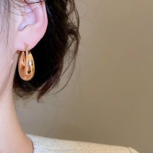 Gros plan d'un mannequin portant des boucles d'oreilles gouttes dorées polies et chic