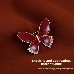 Close-up of red enamel butterfly brooch with gold plating and cubic zirconia accents