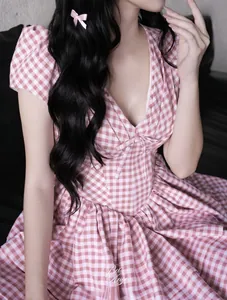 Detail of pink gingham mini dress featuring V-neckline and decorative bow on chest