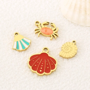 Macro detail of gold enamel ocean charms featuring crab and colorful sea shells