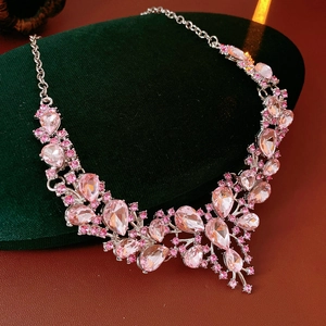 Macro shot of luxury pink teardrop crystal necklace displayed on dark green velvet