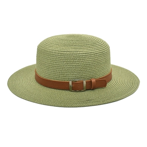 Detalle de un sombrero de paja verde claro elegante con hebilla de cuero marrón