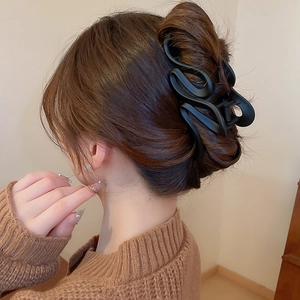 Close-up of matte black wavy hair claw clip used for an elegant hair bun styling