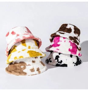 Close-up of soft plush cow print bucket hats in pink yellow brown and black colors