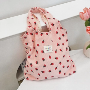 Gros plan d'un sac cabas en velours côtelé rose avec imprimé fraise et étiquette