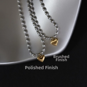 Close-up of heart necklace showing polished and brushed textures with bead chain