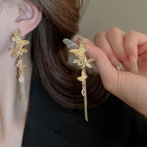 Detail of elegant gold butterfly earrings with long fringe chains and sparkling crystals