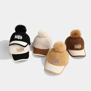 Detail of colorful kids' baseball caps with plush pom-poms and Vibrant Steps embroidery