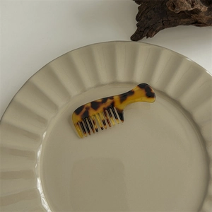 Close-up of mini tortoiseshell pattern hair comb on a rippled edge ceramic plate