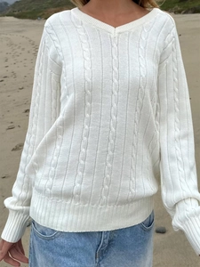 Women's casual white V-neck cable knit sweater with long sleeves in a relaxed beach setting