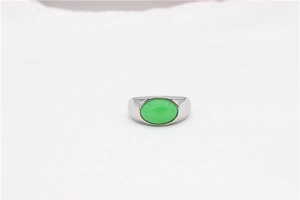 Detailed close-up of a silver ring with an oval green gemstone on white fabric