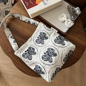 Detail of butterfly print on off-white canvas shoulder bag with vintage literary style