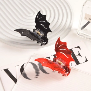 Detail view of bat-shaped hair claws in black and red marble resin on a Vogue magazine