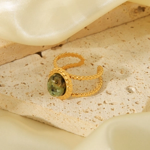 Detailed macro view of vintage gold ring featuring a green natural oval stone and beaded edges