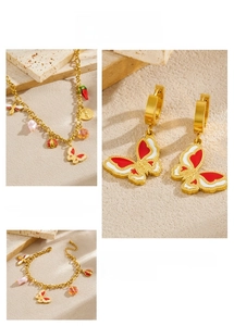Detailed view of golden jewelry set featuring red butterfly and strawberry charms