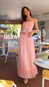 Detail of pink pleated two-piece set featuring a bow strap top and long skirt