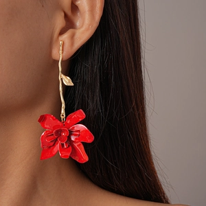 Close-up of red flower drop earring with golden branch stud worn by a model