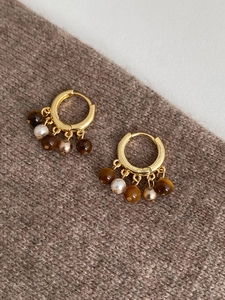 Gros plan de boucles d'oreilles en or 18 carats avec oeil de tigre et perles sur pull
