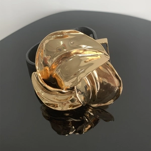Detailopname van een gouden metalen bloemornament met een zwarte lederen band