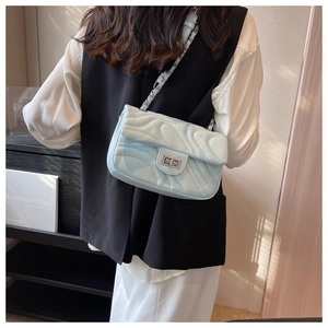 Detail of light blue quilted crossbody bag with silver chain strap and twist lock