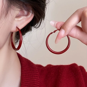Close-up of red circular hoop earrings showing glossy finish and hinge clasp mechanism