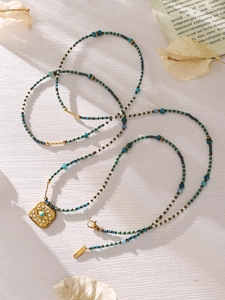 Detail of stainless steel evil eye pendant necklace with turquoise bead chain links