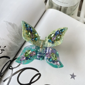 Close-up of butterfly hair claw clip featuring gradient acetate and sparkling rhinestones