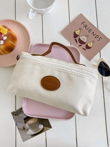 Close-up of beige nylon toiletry bag with leather patch and handle in a lifestyle setting