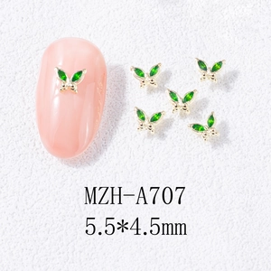 Macro shot of gold-edged green crystal butterfly nail charms sized 5.5x4.5mm