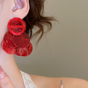 Close-up of red sequin circular drop earrings worn by a model for a stylish vacation look