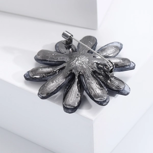 Minimalist dark grey acrylic flower brooch with metal pin on a white display stand