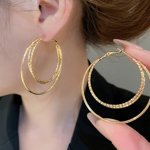 Detailed view of 18k gold plated triple-layer circular hoop earrings on a model