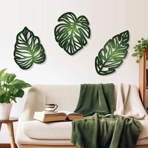 Set of 3 green metal monstera leaf wall art decor displayed above a modern living room sofa