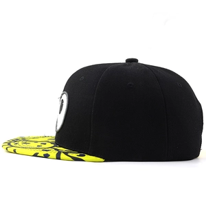 Detail of black snapback with yellow graffiti brim and white eye patch embroidery