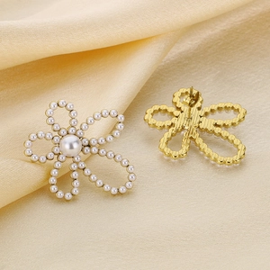 Elegant gold hollow flower petal earrings with white pearls on premium satin fabric