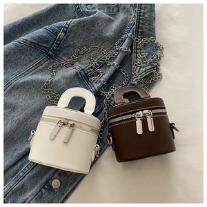 Sacs cylindriques en cuir PU blanc et marron posés sur une veste en jean