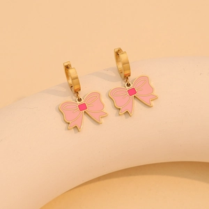 Close-up of pink enamel bow earrings with gold-tone finish on a white display stand