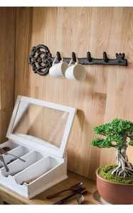 Detail of vintage cast iron key coat rack with four hooks on light wooden wall