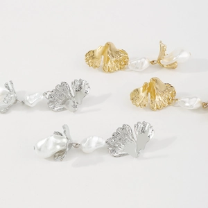 Detail of ginkgo leaf earrings with baroque pearls in gold and silver finishes