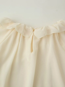 Dettaglio del colletto a balze e chiusura a bottone sul retro della blusa in chiffon