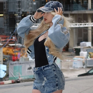 Close-up of light blue distressed denim jacket with frayed edges and cropped fit